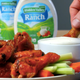 Hand dips buffalo chicken wing into bowl of ranch dressing